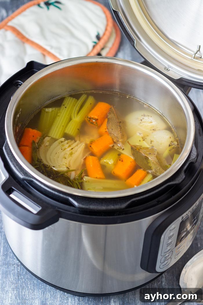 Turkey stock in an open pressure cooker with carrots, celery, onions and herbs.