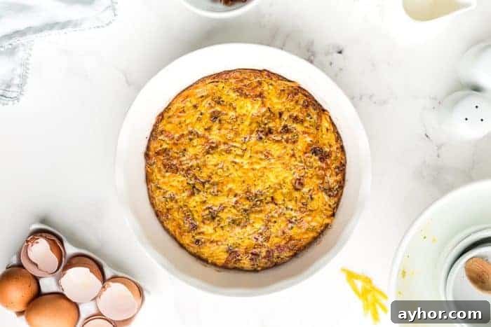 baked low carb quiche in a white pie pan next to broken eggs