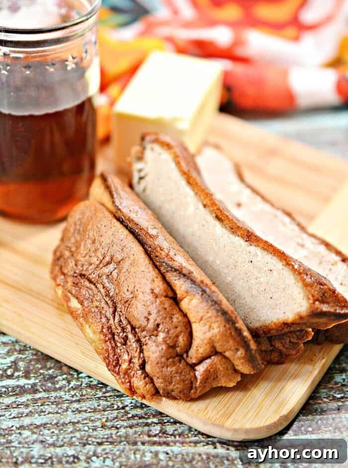 side shot of keto eggloaf sliced on a nice wooden cutting board by a glass of keto syrup