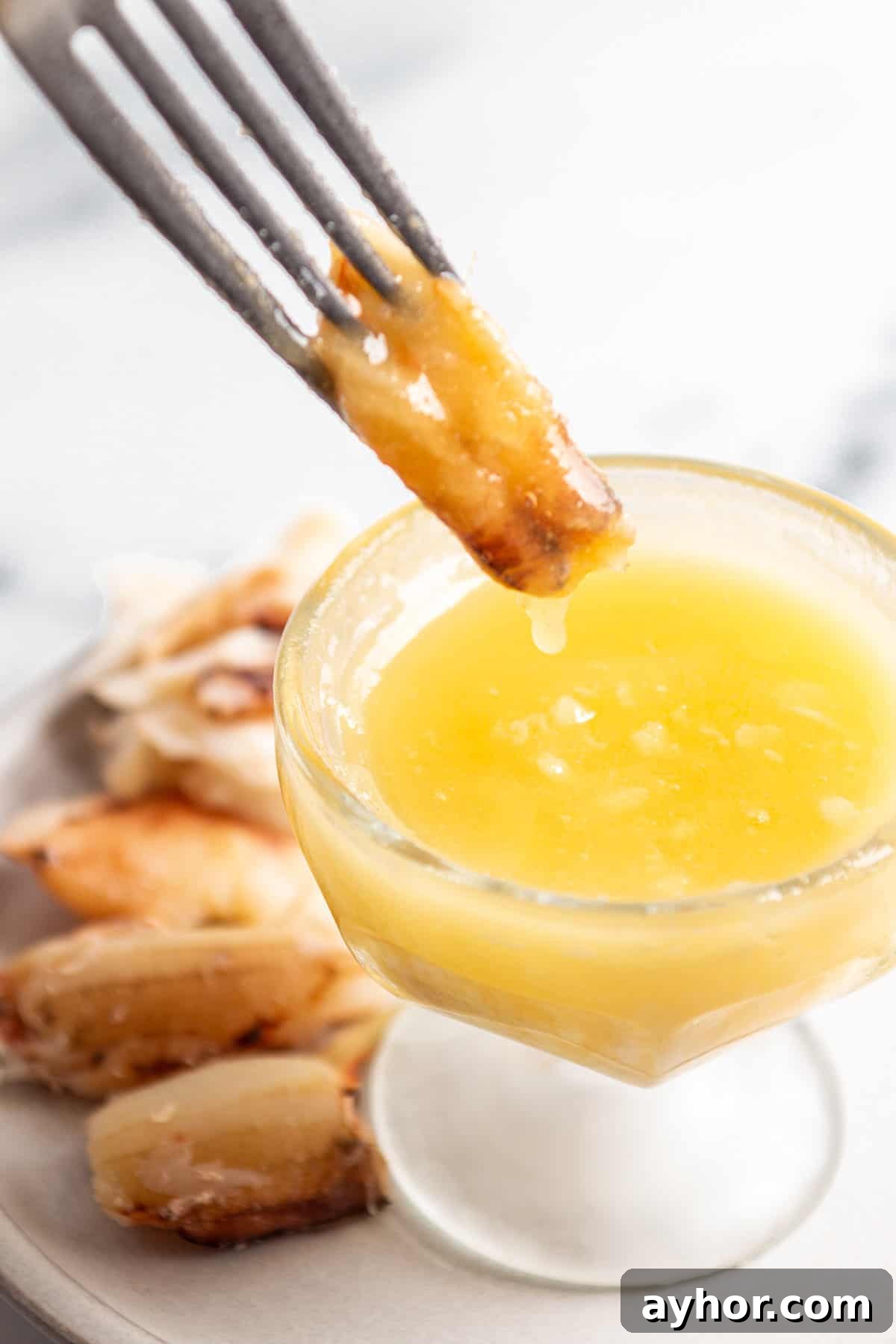 Garlic Butter Sauce Recipe for Seafood and Shellfish 2 A fork dipping a piece of crab into a bowl of garlic butter.