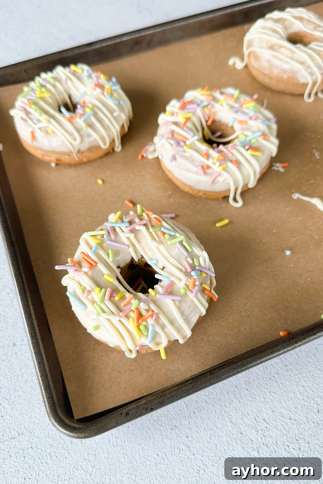 Moist Baked Carrot Cake Donuts with Cream Cheese Glaze 7 Baked carrot cake donuts on a pan.