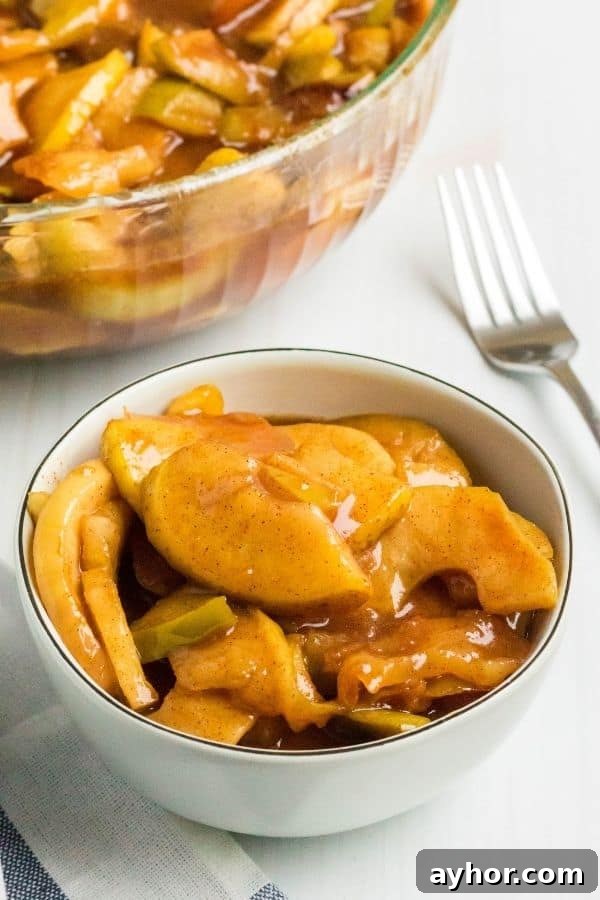 Instant Pot Cinnamon Apples: Quick Spiced Apple Dessert 3 a cream-colored bowl filled with Instant Pot fried apples, with a serving bowl full of cinnamon apples in the background