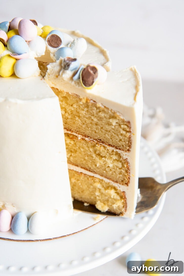 triple layer cake slice being pulled out of vanilla cake garnished with cadbury mini eggs