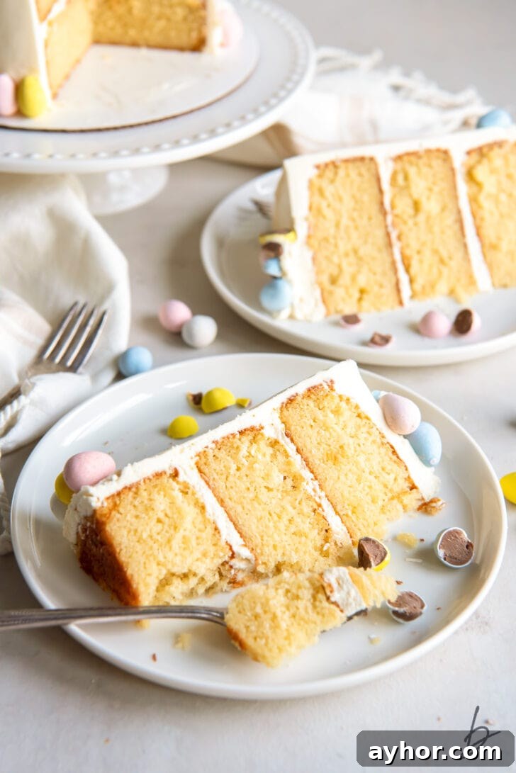 triple layer cadbury mini egg cake slice on plate with fork taking bite and another plate with cake slice behind it