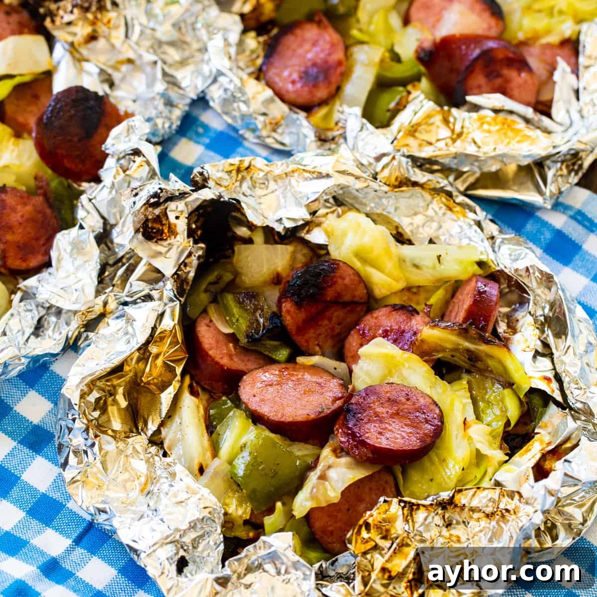 Keto Sausage and Cabbage Foil Packets for Quick Low-Carb Meals 2 Keto Cabbage and Sausage Foil Packs on a blue and white cloth napkin.