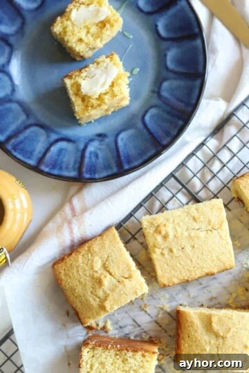 Sliced cornbread on blue plate with butter and honey.