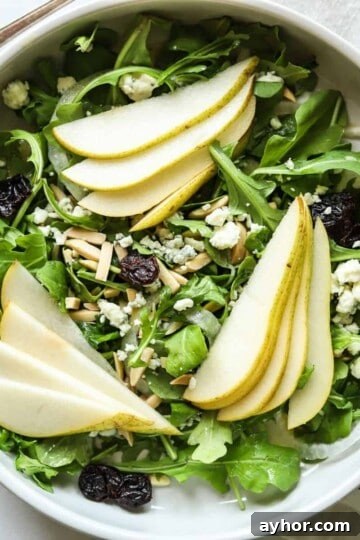 overhead view of rocket and pear salad in white bowl