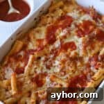 Meatless baked ziti in casserole dish with sauce on side.