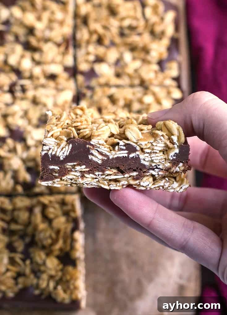 a hand holding a gluten free oatmeal chocolate fudge bar, showing the layers