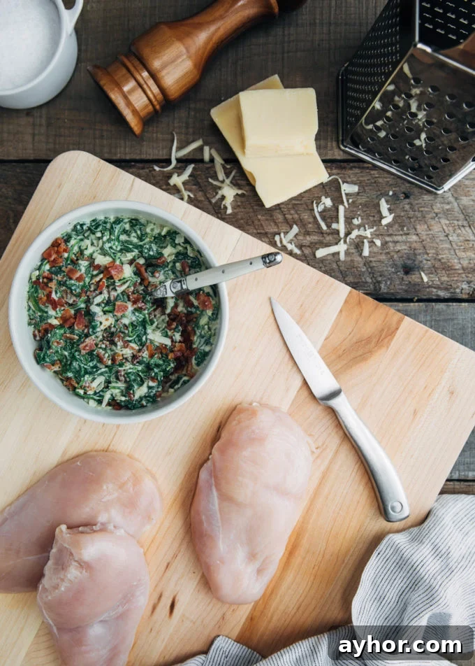 raw chicken breasts on a board with a bowl of creamed spinach filling