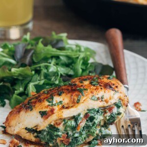 spinach stuffed chicken breast on an ivory plate with salad greens