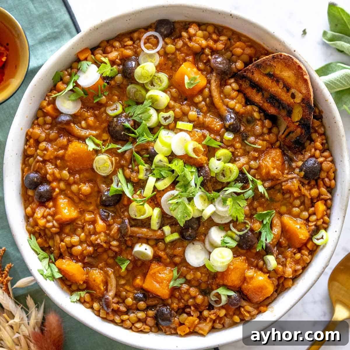 Lentil stew with scallions in a bowl and a slice of bread