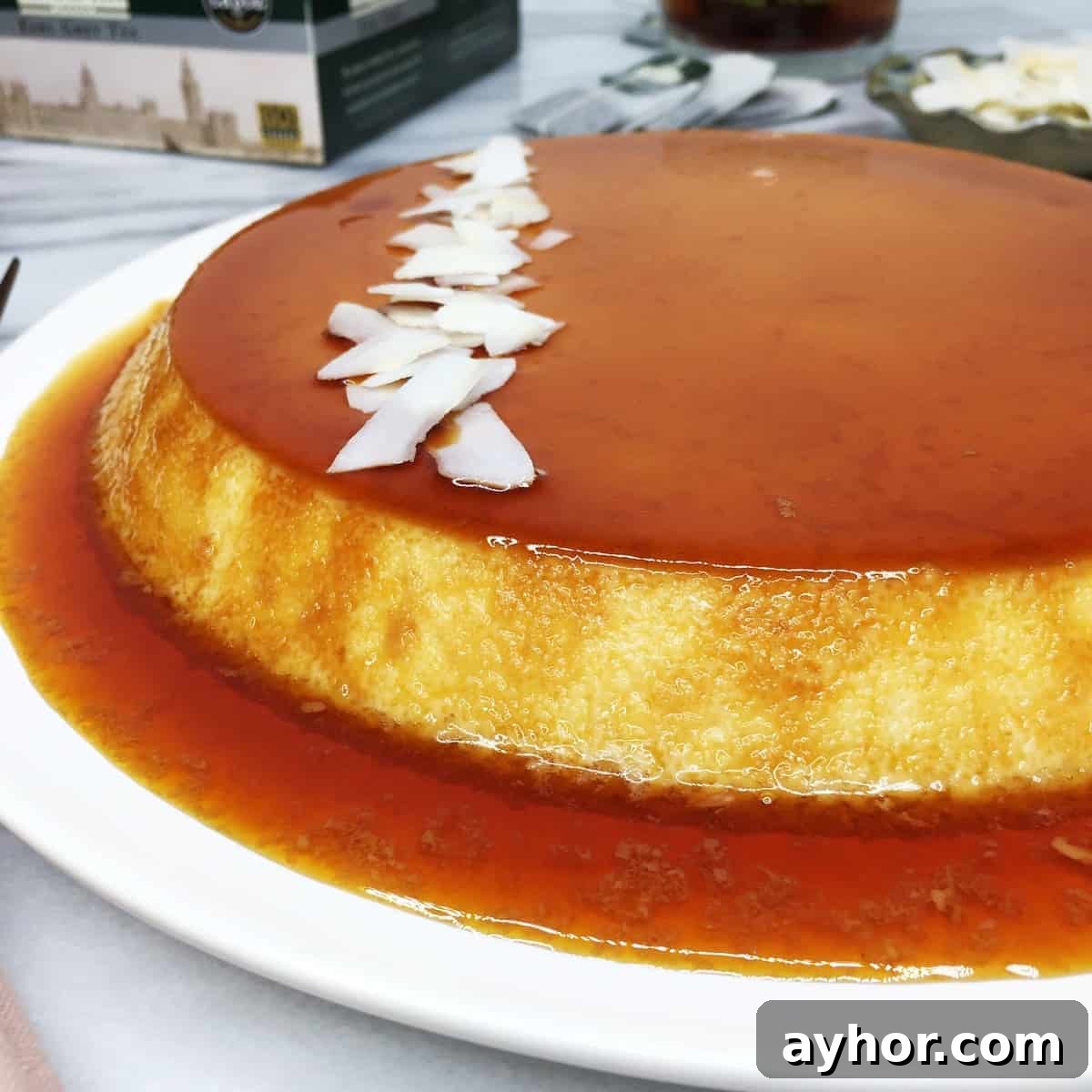 Coconut flan decorated with coconut chips and served on a white plate.