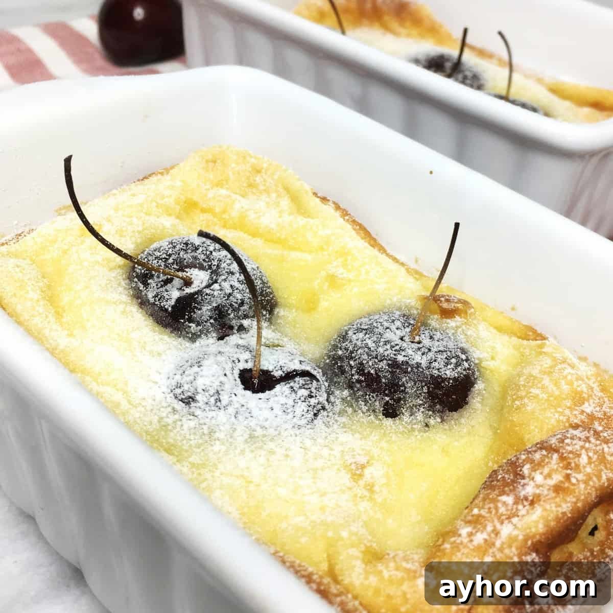 Ready cherry French dessert clafoutis served in individual dishes on a striped kitchen towel.