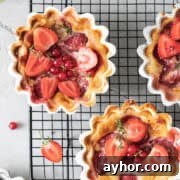 Warm strawberry clafoutis desserts resting on a wire rack after baking.