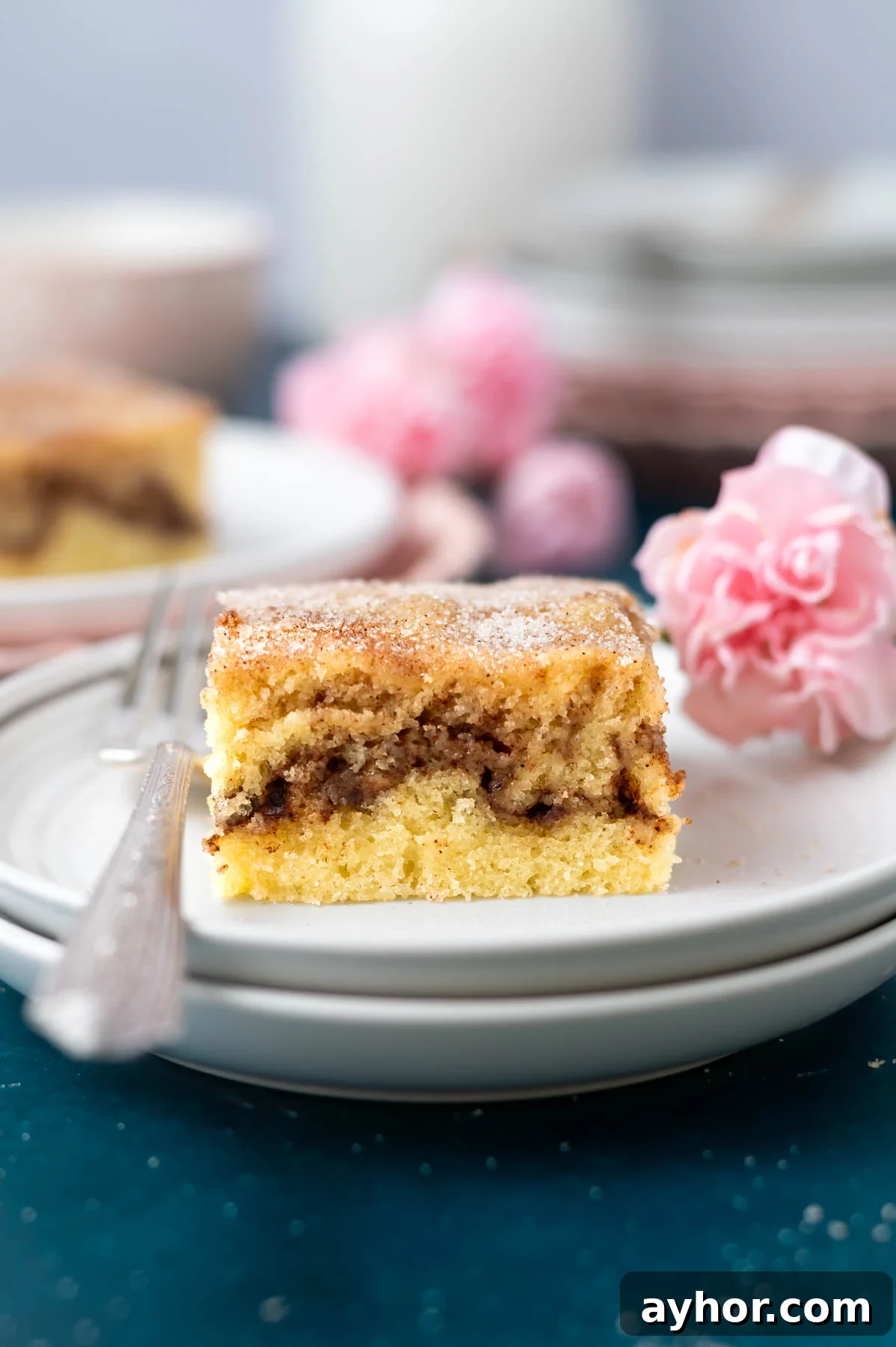 slice of cake on a plate with a fork and a pink flower