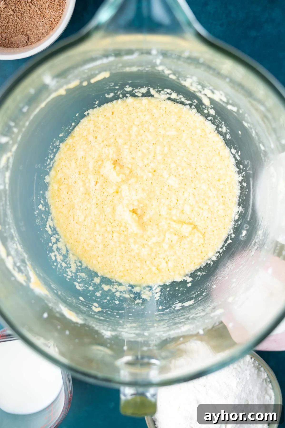 butter, sugar and eggs mixed together in a mixing bowl looking a little curdled