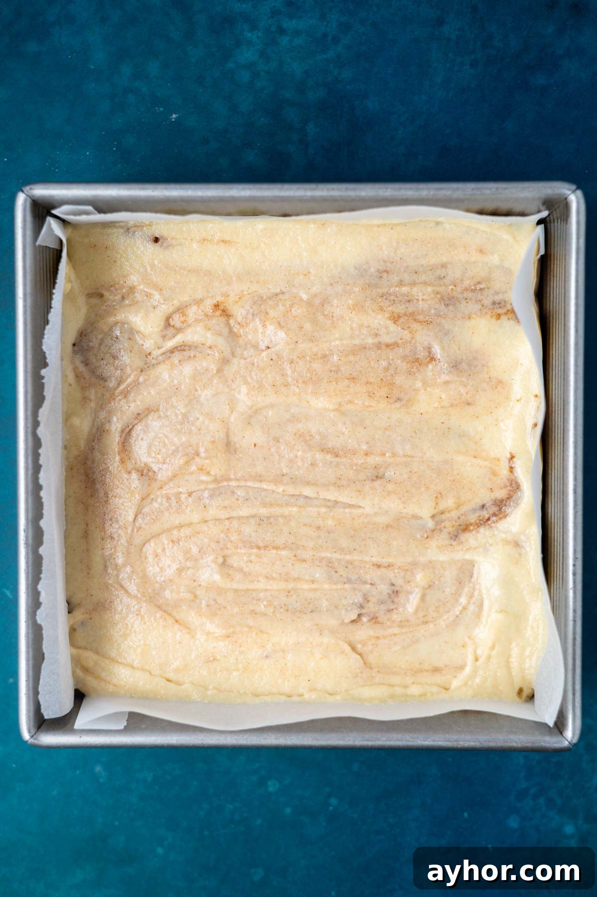 cinnamon swirled cake batter in a parchment lined baking pan