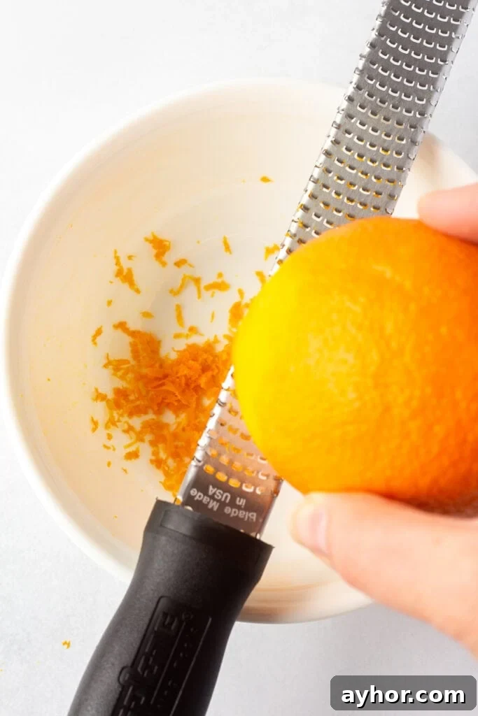 Honey Orange Vinaigrette with 6 Simple Ingredients 4 Close up of zesting an orange with a microplane over a medium white bowl.