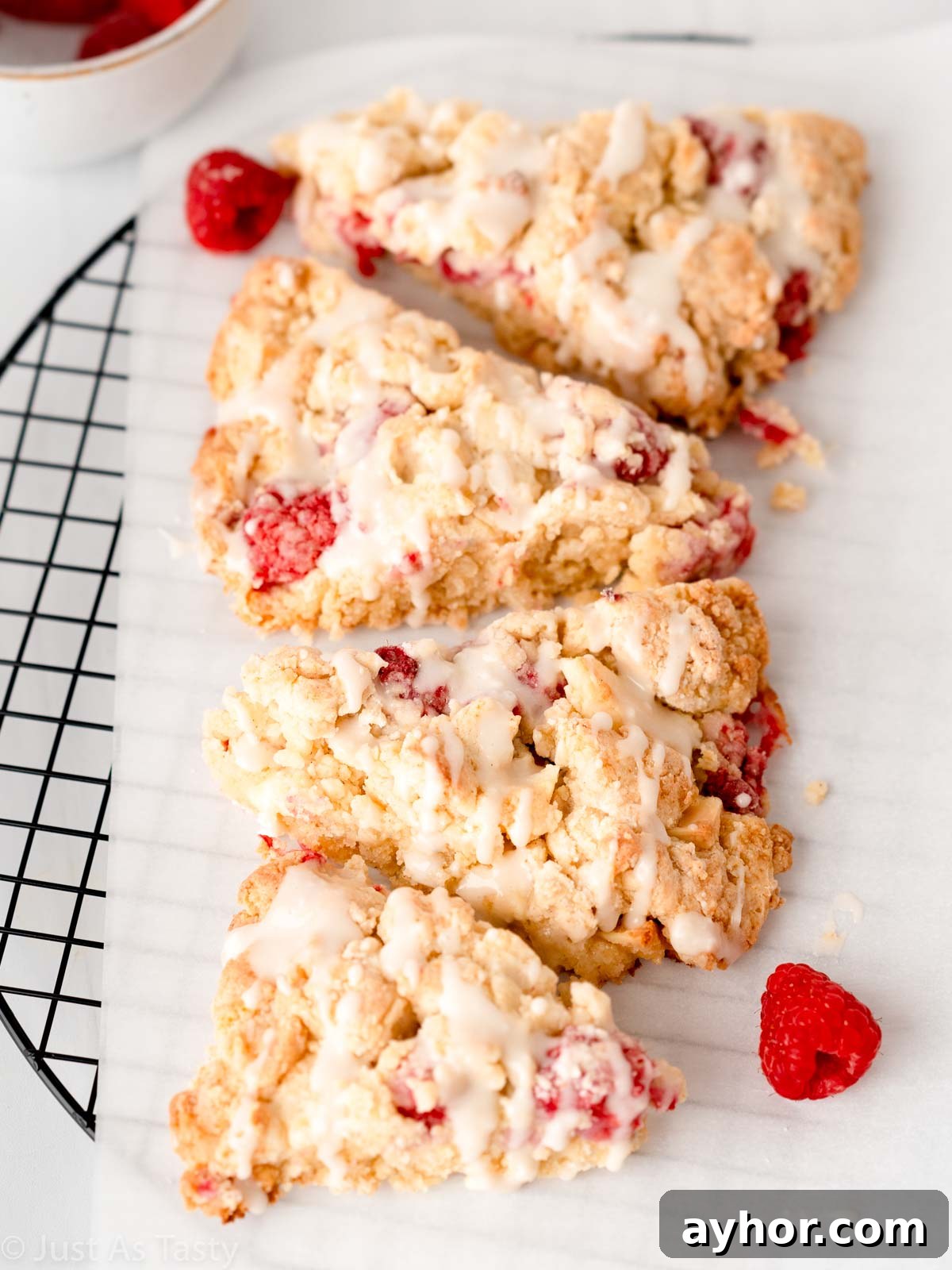 White Chocolate Raspberry Scones Recipe - Tender Morning Treat 2 Four glazed white chocolate raspberry scones on parchment paper.