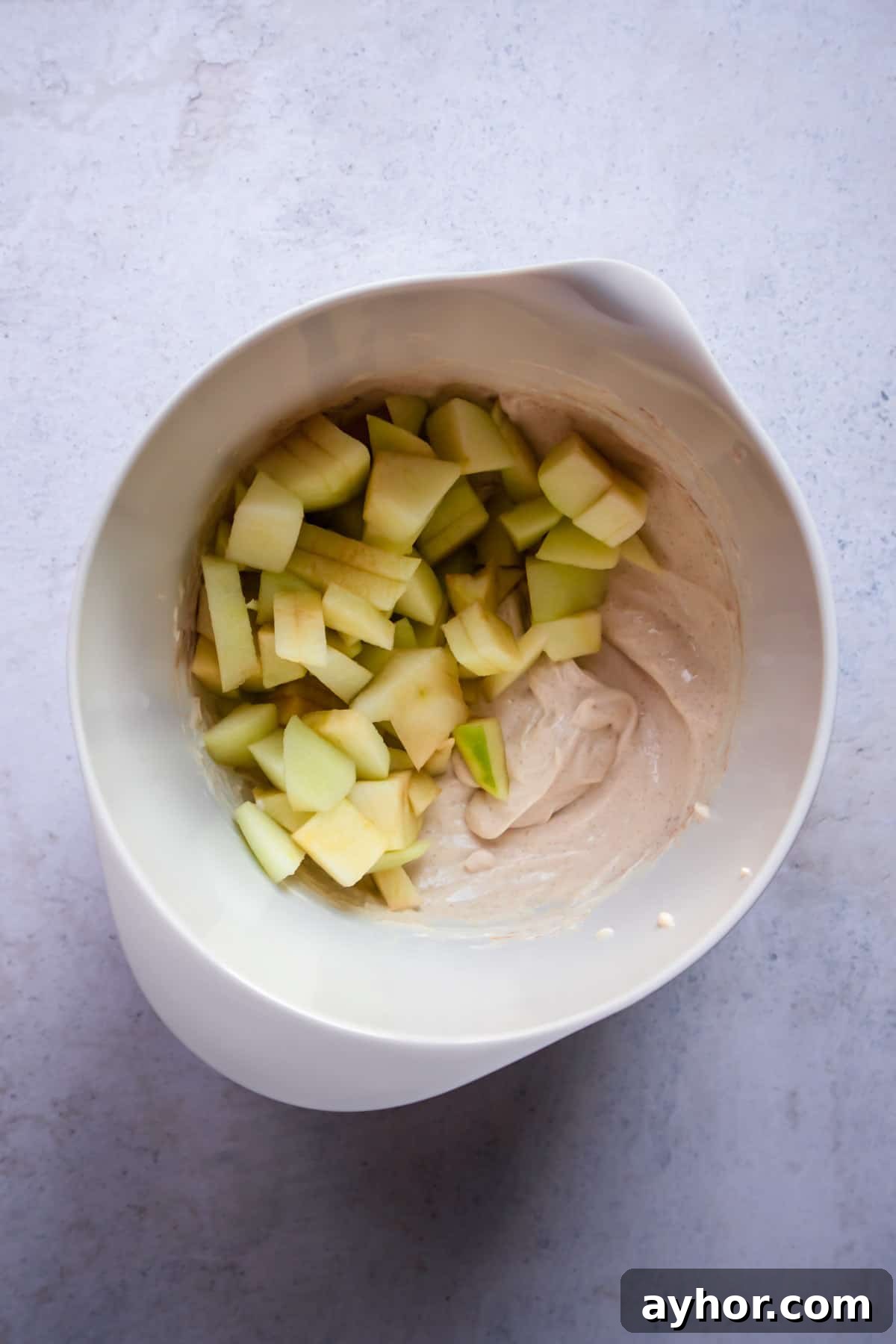 Cinnamon Apple French Toast Bake with Crisp Topping 5 chopped apples on top of a cream cheese cinnamon mixture in a bowl