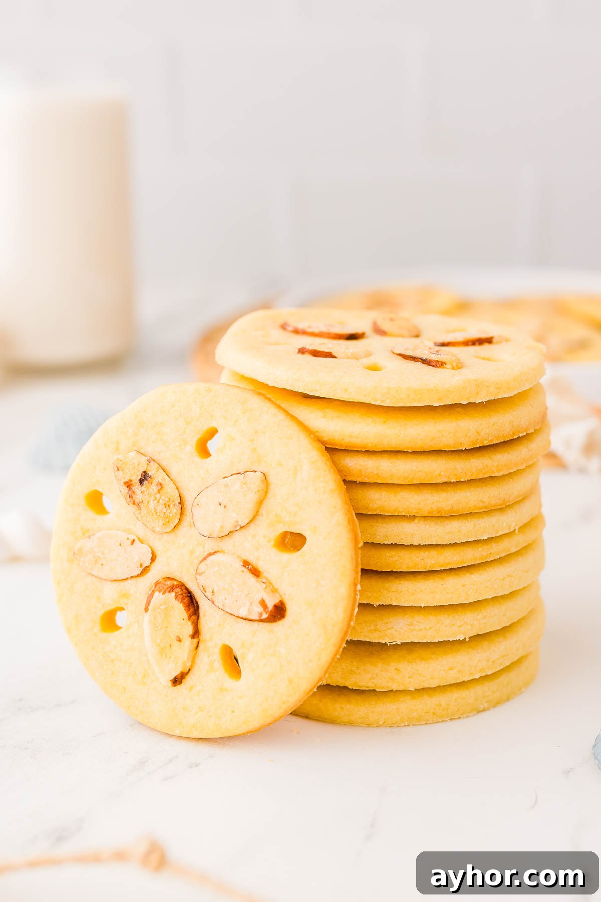 Sand Dollar Cookie Recipe: Crisp Shortbread Cookies Shaped Like Sand Dollars 3 A stack of round cookies with almond slices arranged in a flower pattern on each, placed on a white surface.