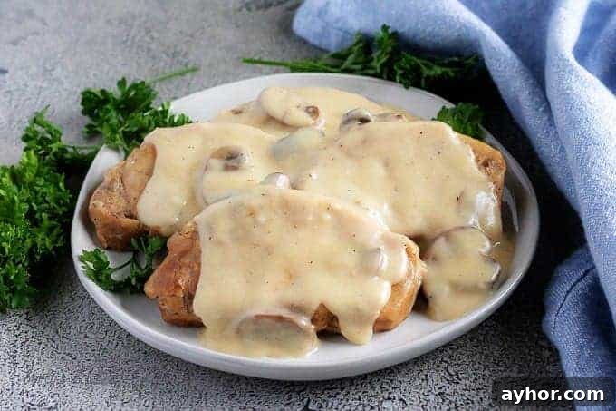 Instant Pot Pork Chops in Creamy Mushroom Gravy 2 Instant Pot pork chops with mushroom gravy on a gray plate.