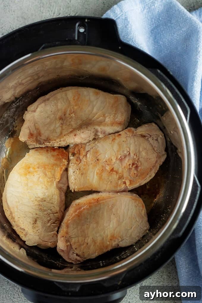 Instant Pot Pork Chops in Creamy Mushroom Gravy 4 A top-down view of the seared pork chops in the Instant Pot.