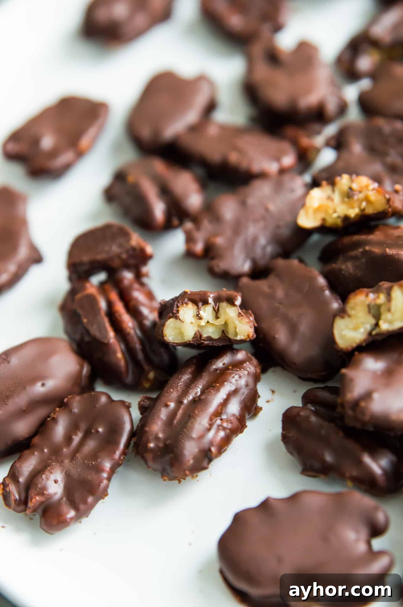 Homemade Chocolate-Covered Pecans: Simple No-Bake Recipe 2 A plate of chocolate covered pecans, with a bite out of one of them.