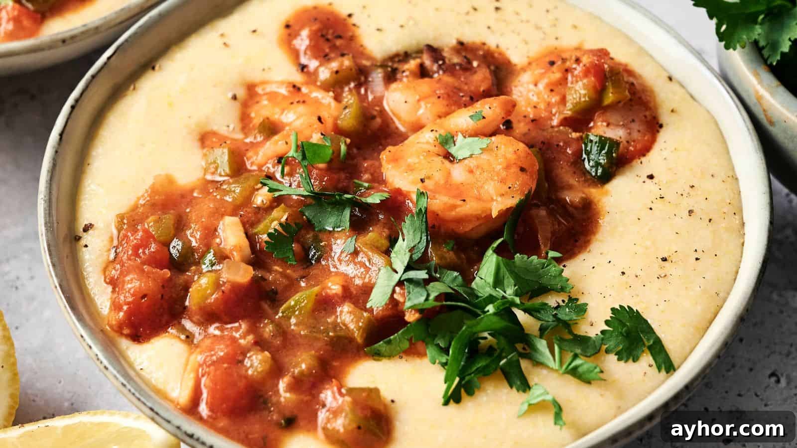 29 Breakfast Recipes to Make Your Mornings Feel Romantic 13 A bowl of creamy grits topped with shrimp in a tomato-based sauce and garnished with fresh parsley.