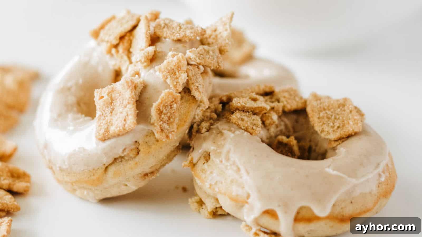 29 Breakfast Recipes to Make Your Mornings Feel Romantic 28 Two glazed donuts topped with crumbled cereal pieces are placed on a white surface.