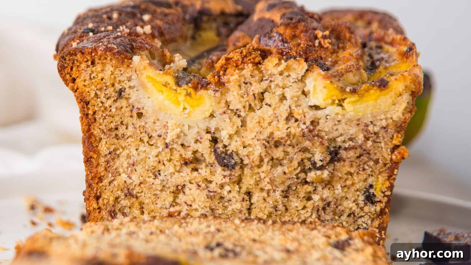 29 Breakfast Recipes to Make Your Mornings Feel Romantic 5 Close-up view of a sliced banana bread loaf with visible chunks of banana and nuts on a white plate.