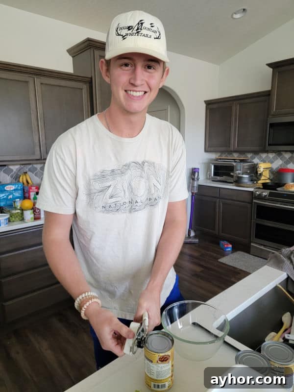 Young man opening a can of kidney beans in a kitchen