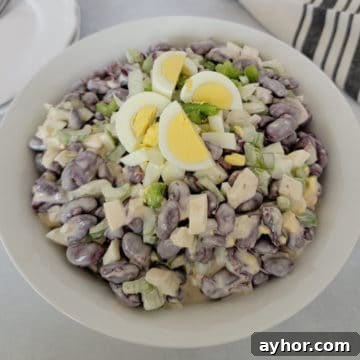 Kidney Bean Salad with hard boiled egg pieces on top in a white bowl