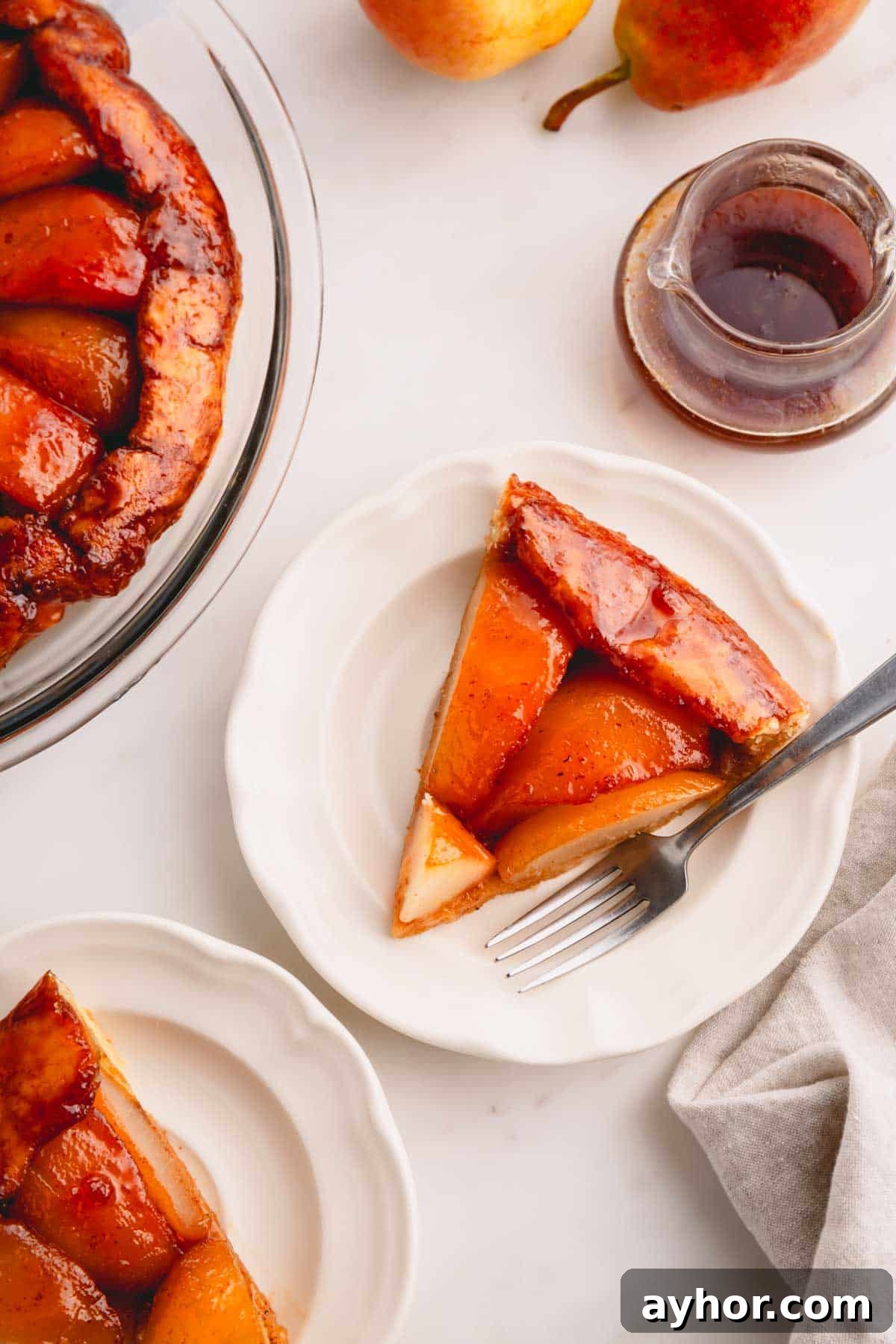 A slice of pear tarte tatin on a plate with a fork.