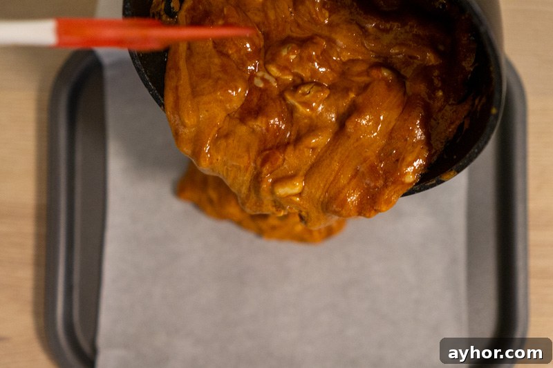Pouring the peanut caramel mixture onto a sheet tray