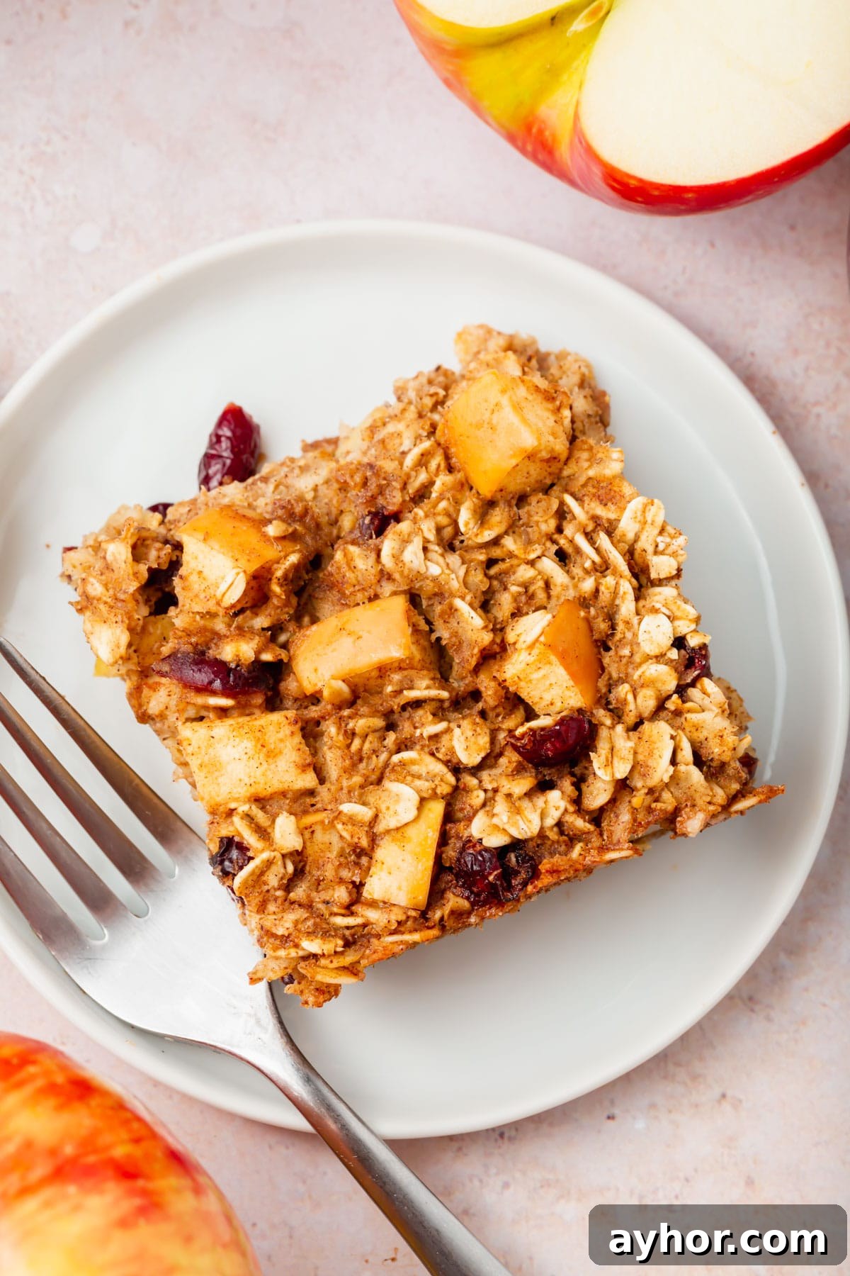 A close-up of a square of gluten-free vegan apple baked oatmeal on a plate drizzled with honey.