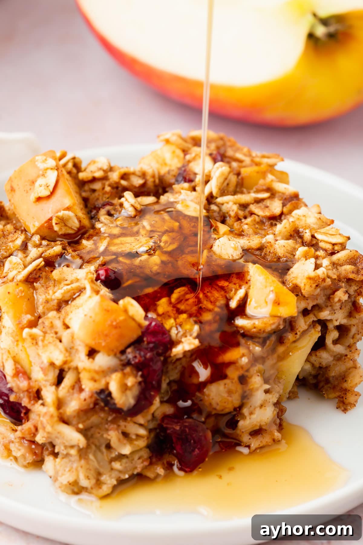 A close-up of a square of gluten-free vegan apple baked oatmeal on a plate drizzled with honey.