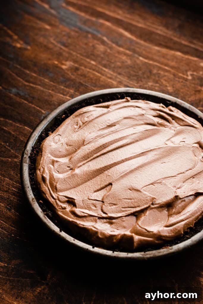 No-Bake Black Forest Chocolate Cherry Pie Recipe 4 Chocolate mousse filling in a chocolate crust in a metal pie plate on a wooden surface