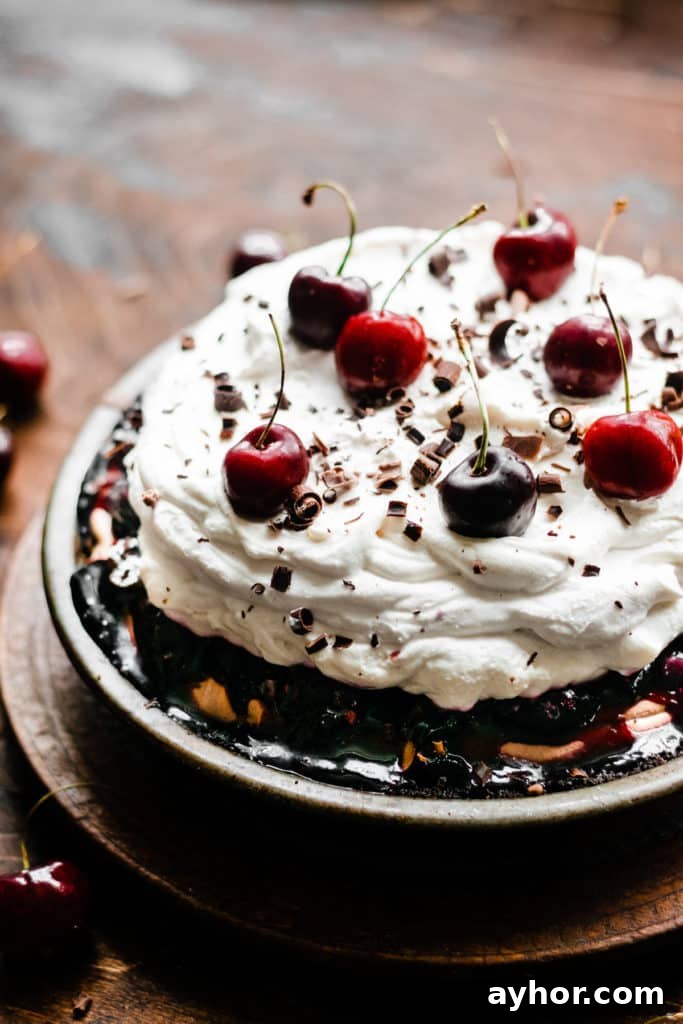 No-Bake Black Forest Chocolate Cherry Pie Recipe 8 A Black Forest Pie, topped with a pile of whipped cream and fresh cherries, on a vintage wooden surface
