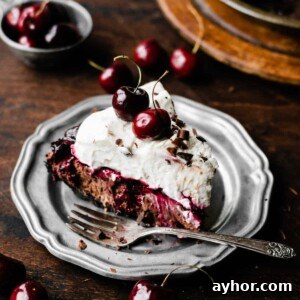 No-Bake Black Forest Chocolate Cherry Pie Recipe 9 A slice of Black Forest Pie on a plate, with a fork and fresh cherries scattered around