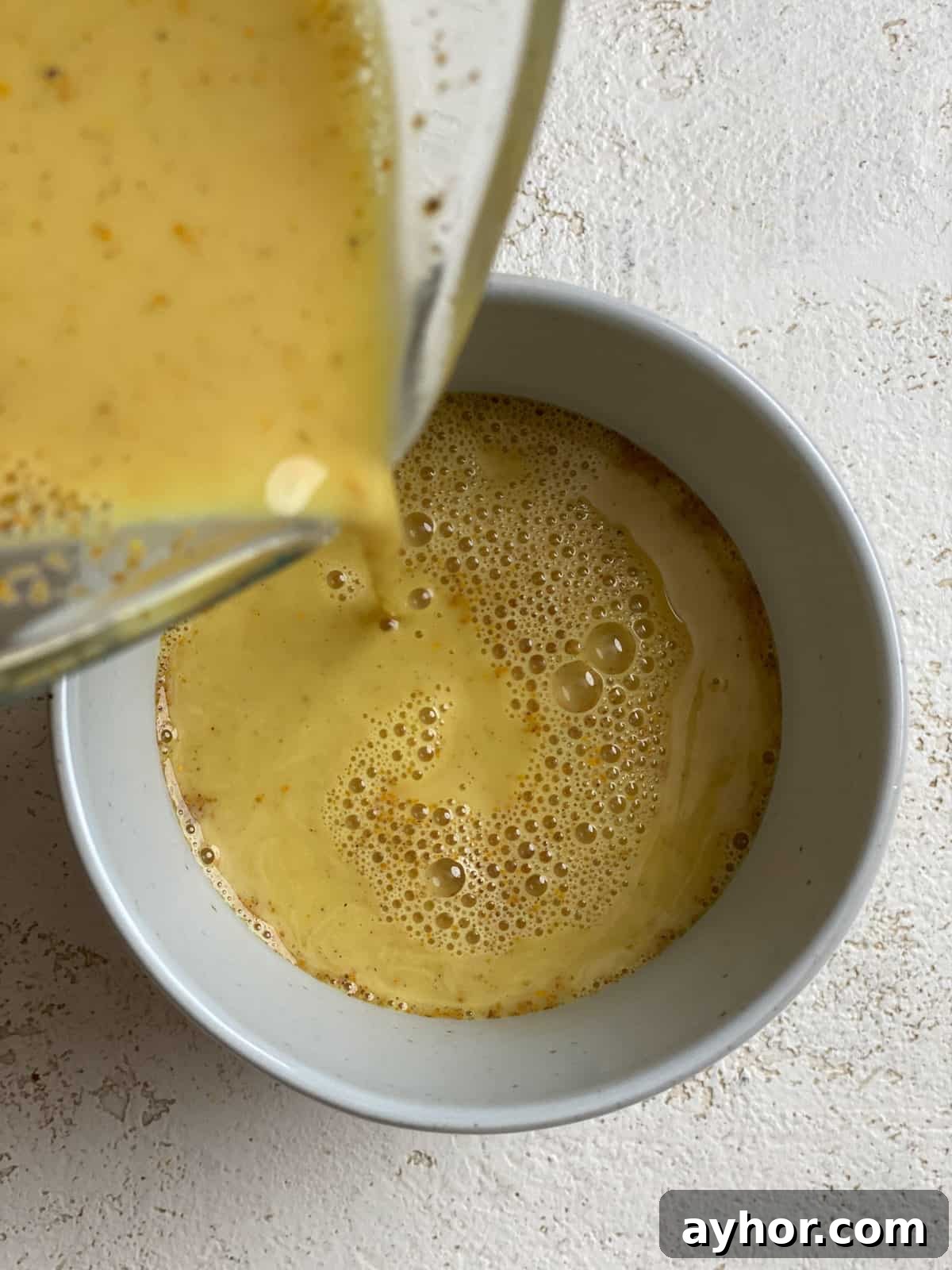 How to Make Turmeric Golden Milk: Creamy Anti-Inflammatory Latte 8 process shot of pouring golden milk into mug