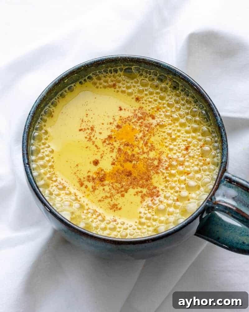 How to Make Turmeric Golden Milk: Creamy Anti-Inflammatory Latte 9 completed golden milk in dark colored cup against white background