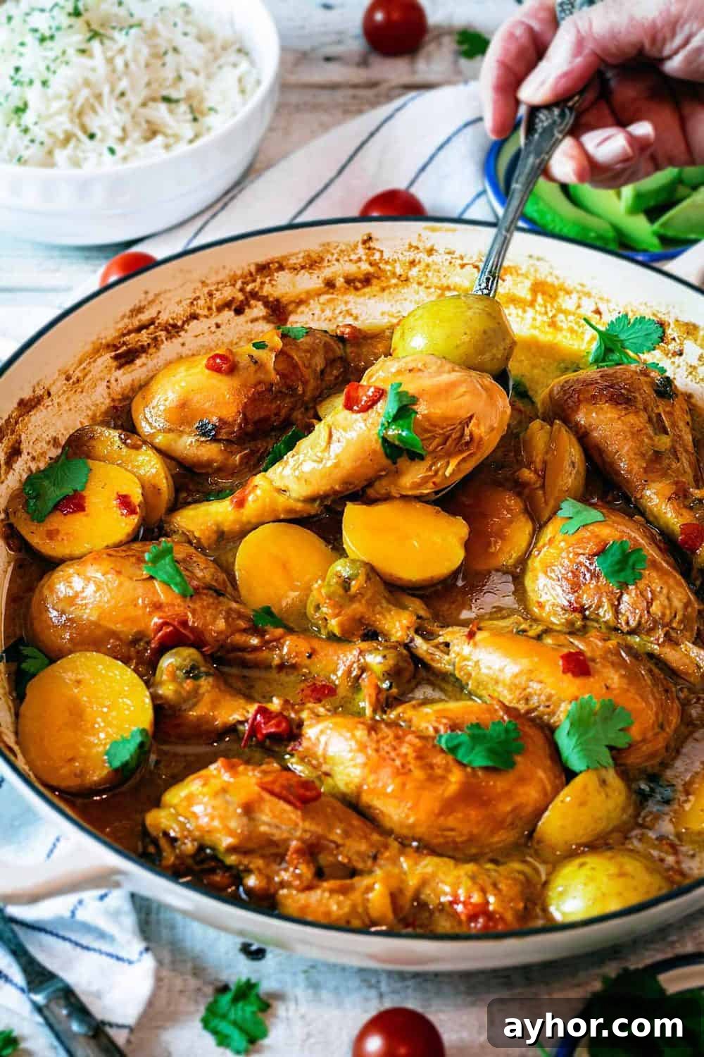 A person digging into the chicken and potato stew with a spoon. 