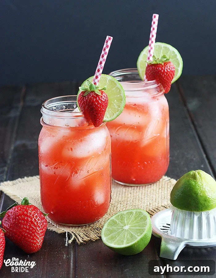 77 Brunch Cocktails to Impress Your Guests 5 Two glasses of vodka lemonade on a wooden background with strawberries and limes surrounding the glasses