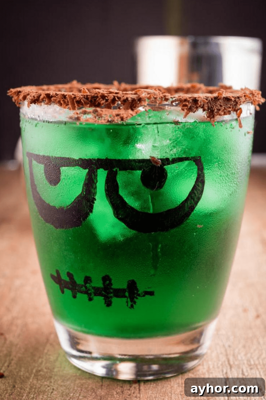 20+ Spooky Halloween Cocktail Recipes for Adults 12 Green halloween cocktail with chocolate rim in Frankenstein glass.