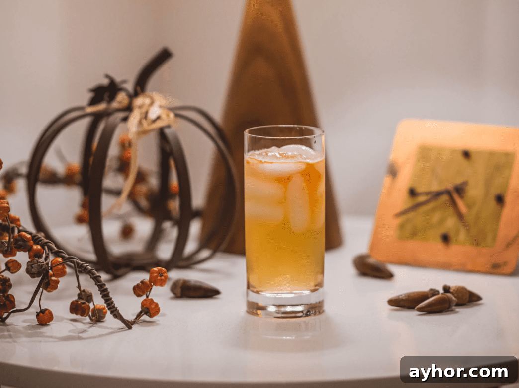 20+ Spooky Halloween Cocktail Recipes for Adults 14 Orange cocktail on table with fall decorations.