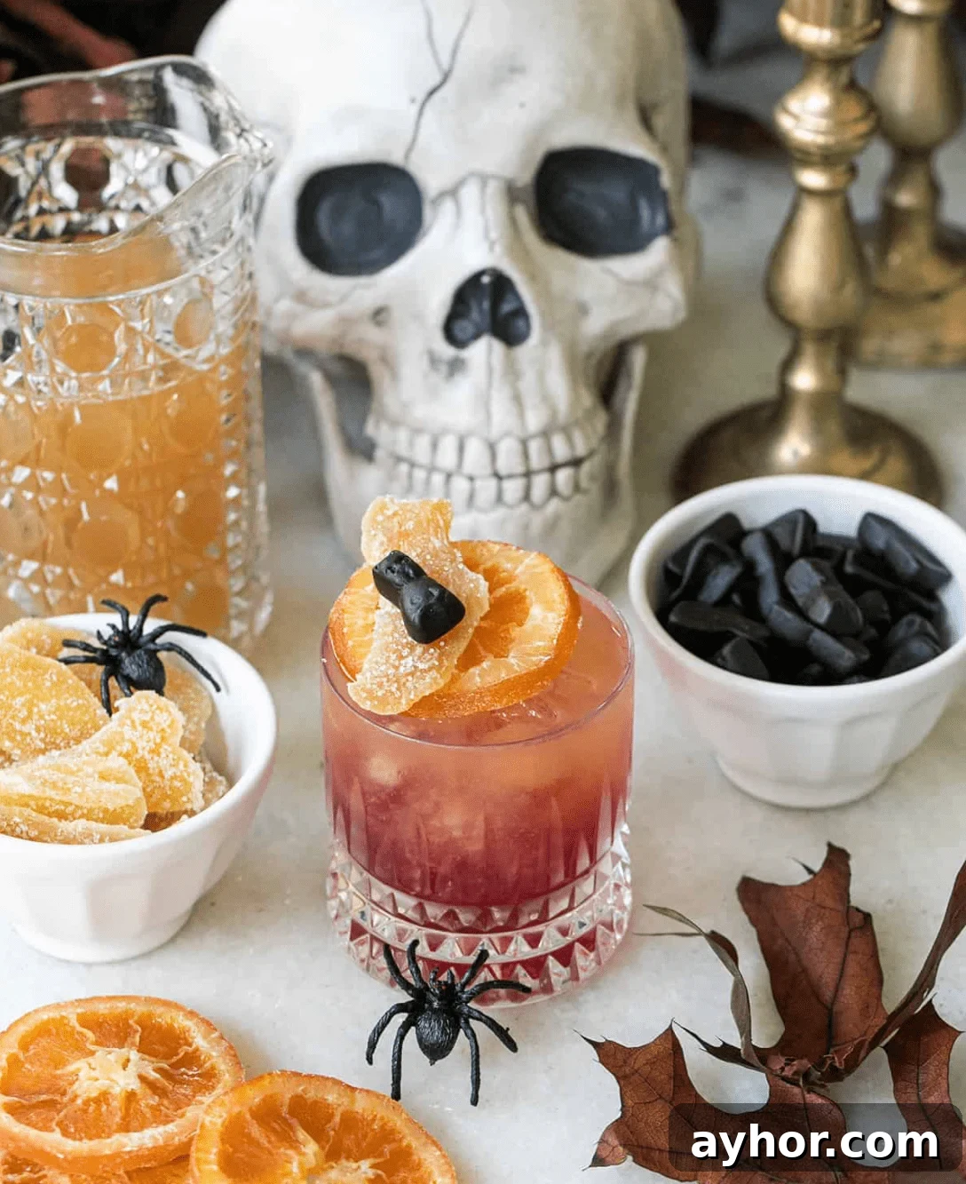 20+ Spooky Halloween Cocktail Recipes for Adults 16 Witch's Brew cocktail on table with halloween decorations and candy.