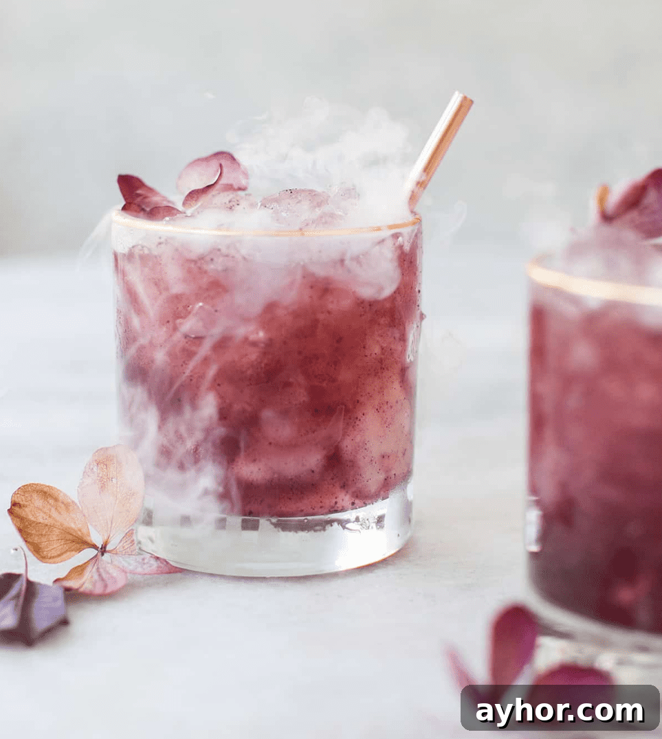 20+ Spooky Halloween Cocktail Recipes for Adults 18 Purple cocktails on a table with flowers and smoke.