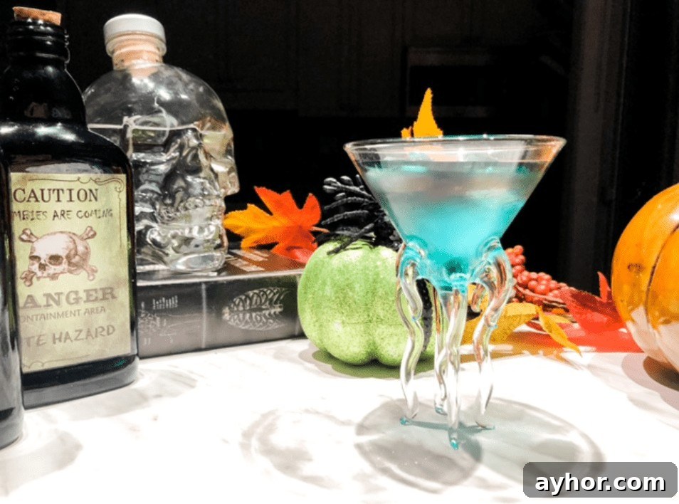 20+ Spooky Halloween Cocktail Recipes for Adults 19 Blue cocktail on table with liquor bottles and fall decorations.